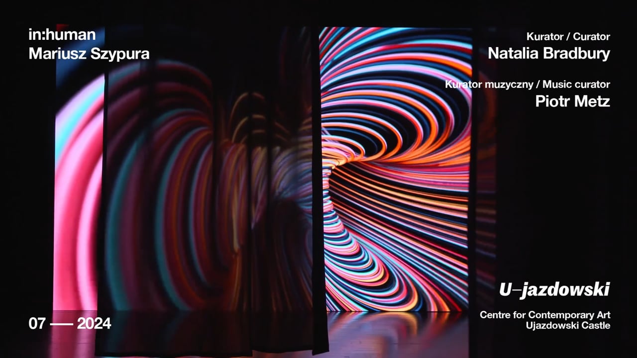 in:human — trailer poster frame: red and pink glittering surface on a black background